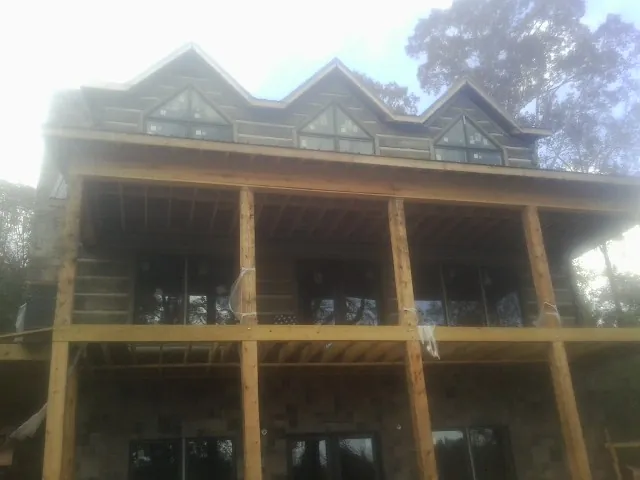 Dormers and porch framing on a large log home under construction — Roof Coating work by our crew in Reading